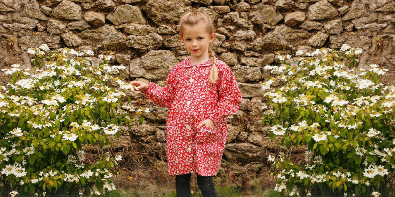 Petite fille portant un tablier d'école rose à fleurs blanches